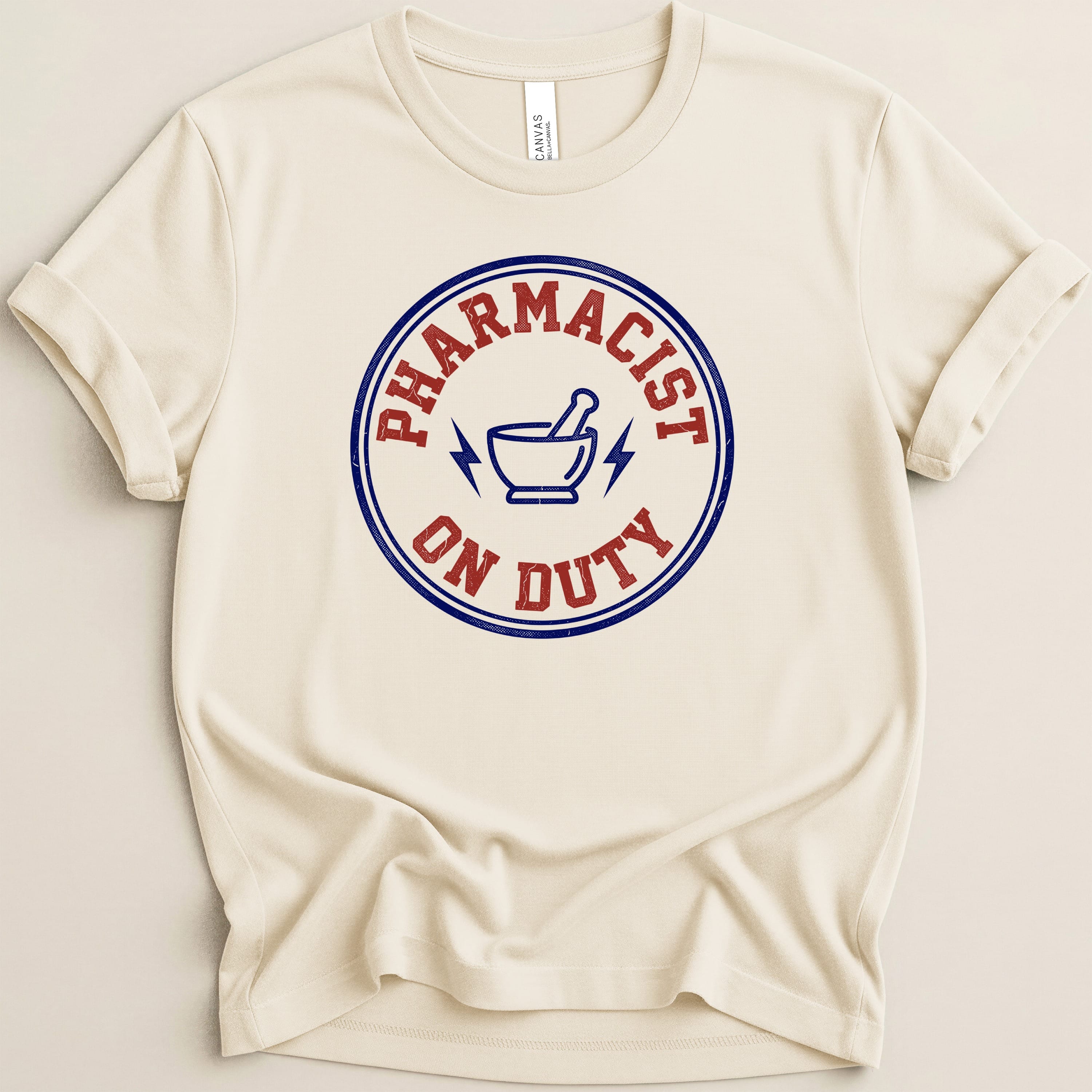 Cream t-shirt with "Pharmacist On Duty" text and lightning bolt symbol.
