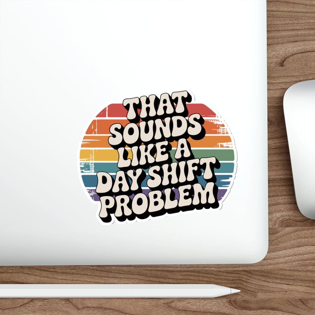 Sticker with retro-style text "That Sounds Like a Day Shift Problem" on a laptop.