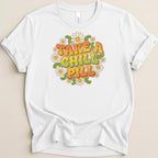 White t-shirt with "TAKE A CHILL PILL" text surrounded by daisies.