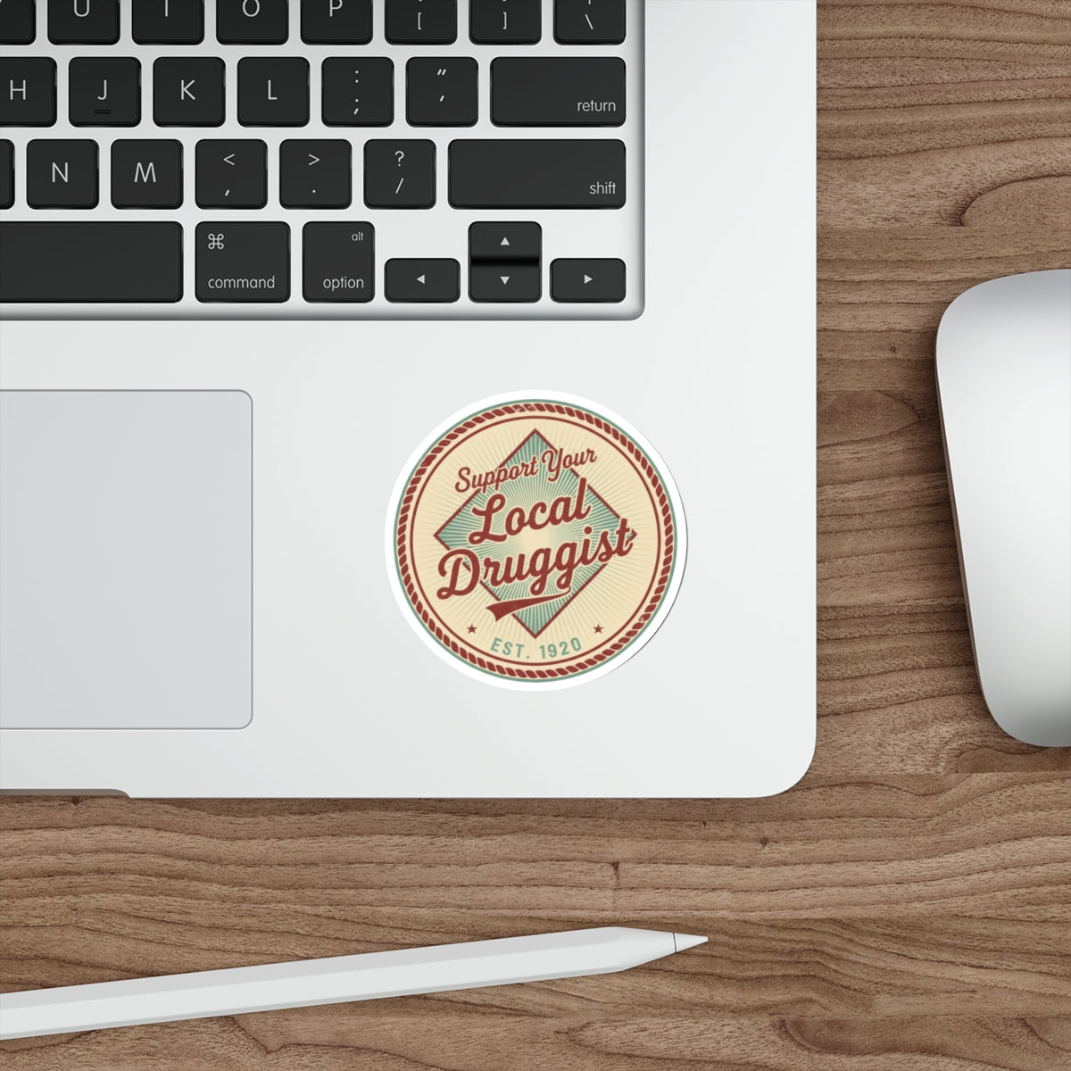 Circular sticker reading "Support Your Local Druggist EST. 1920" on a laptop.