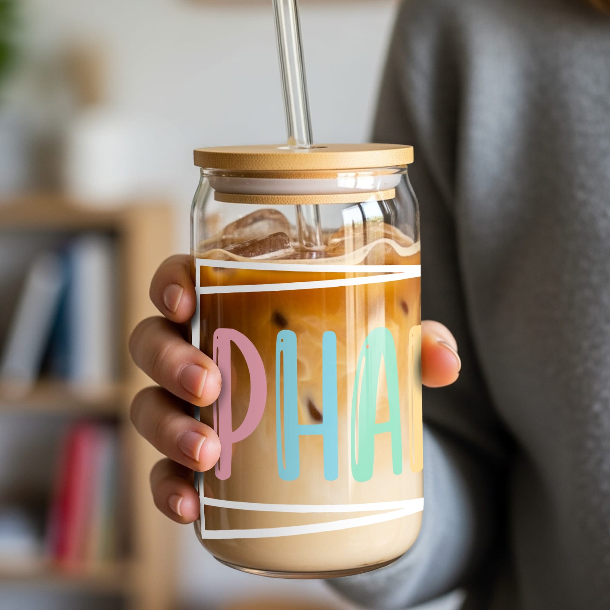 Glass tumbler with straw filled with iced coffee and "PH" text.