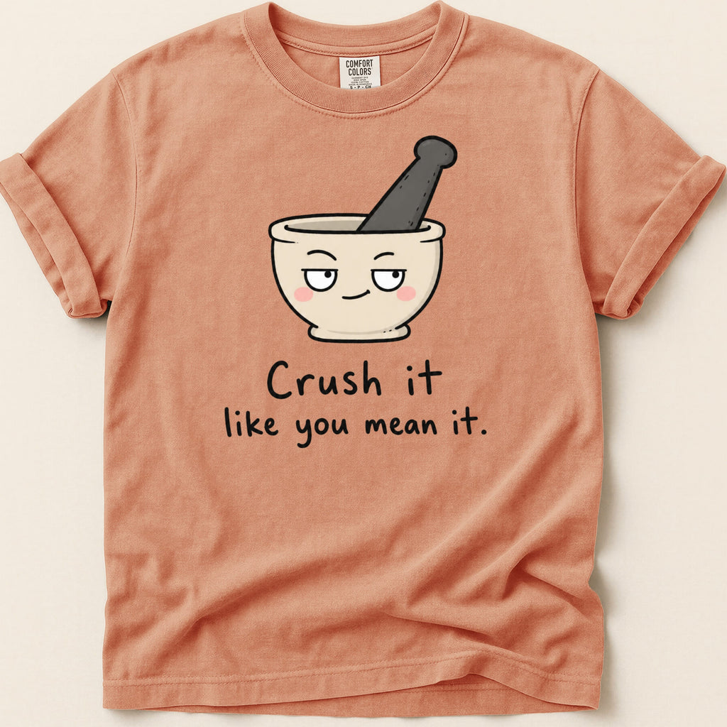 Peach t-shirt with cartoon mortar and pestle and text "Crush it like you mean it."