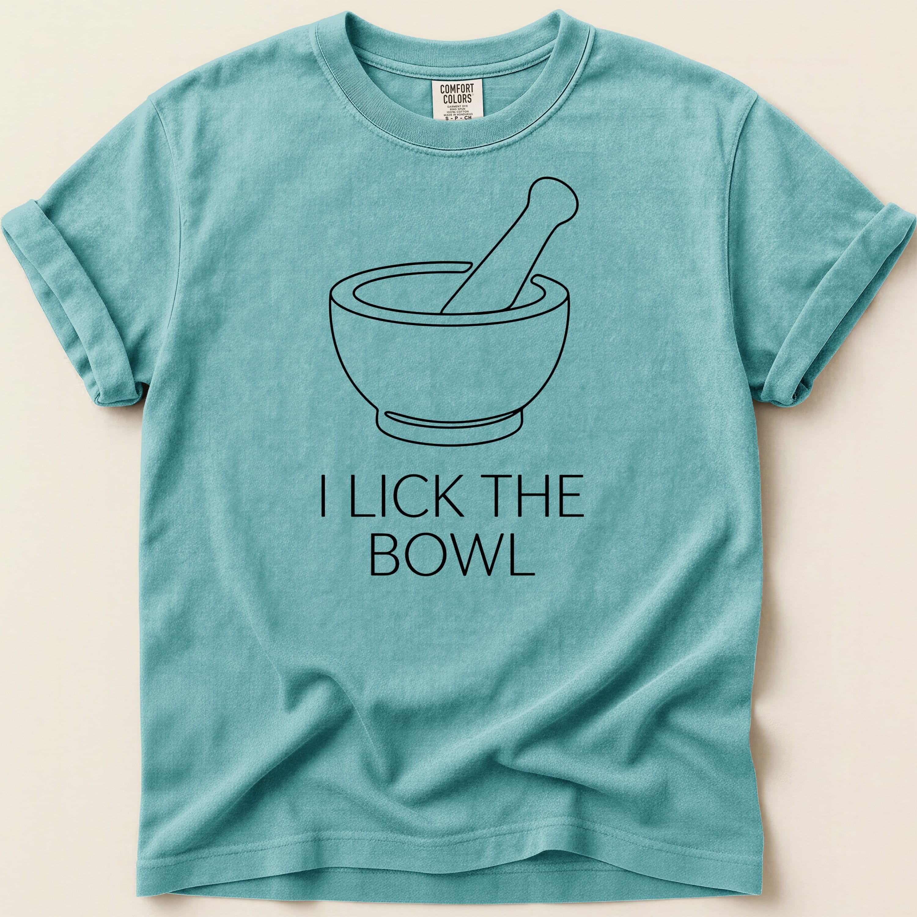 Teal t-shirt with a mortar and pestle graphic and text "I LICK THE BOWL".