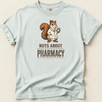 Pale blue t-shirt with a squirrel in a lab coat holding a pill bottle, text reads "NUTS ABOUT PHARMACY".