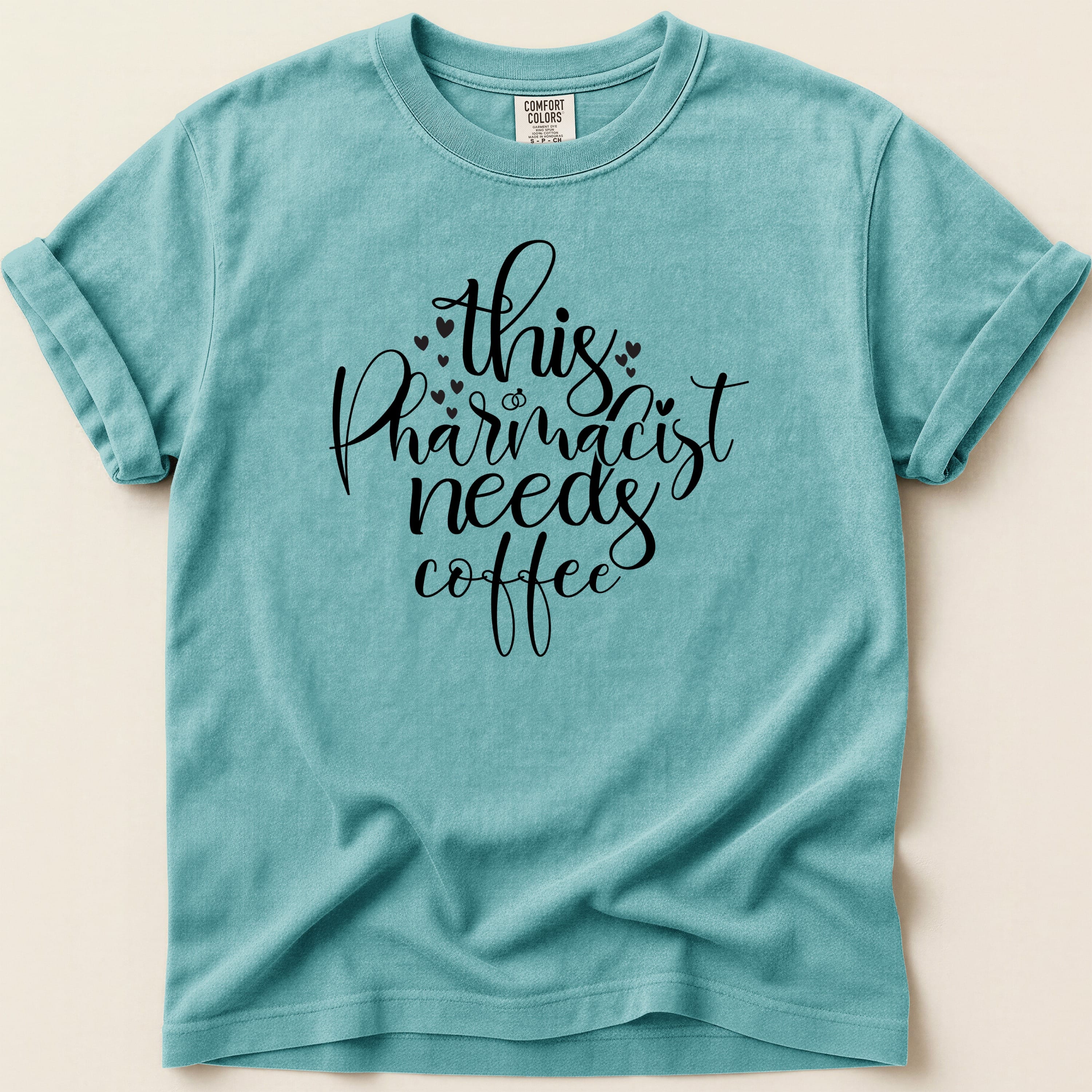 Teal t-shirt with "this pharmacist needs coffee" text in black script.