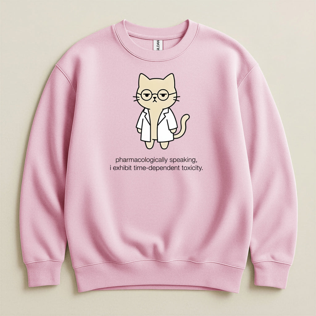 Pink sweatshirt with cartoon cat wearing glasses and lab coat, text reads "pharmacologically speaking, i exhibit time-dependent toxicity."