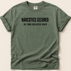 Green t-shirt with "NARCOTICS SECURED IN TIME-DELAYED SAFE" text.