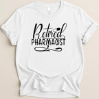 White t-shirt with black text that says "Retired Pharmacist" and a pill icon.