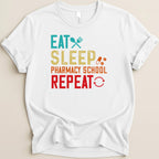 White t-shirt with "Eat Sleep Pharmacy School Repeat" text and icons.