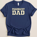 A dark blue crewneck t-shirt featuring the text Pharmacist Dad in distressed white lettering.