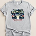 Gray t-shirt with "Trust Your Pharmacist" and "Dose of Care, Daily" text and graphics.
