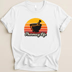 White t-shirt with "Pharmacy Life" text and a mortar and pestle in a sunset graphic.