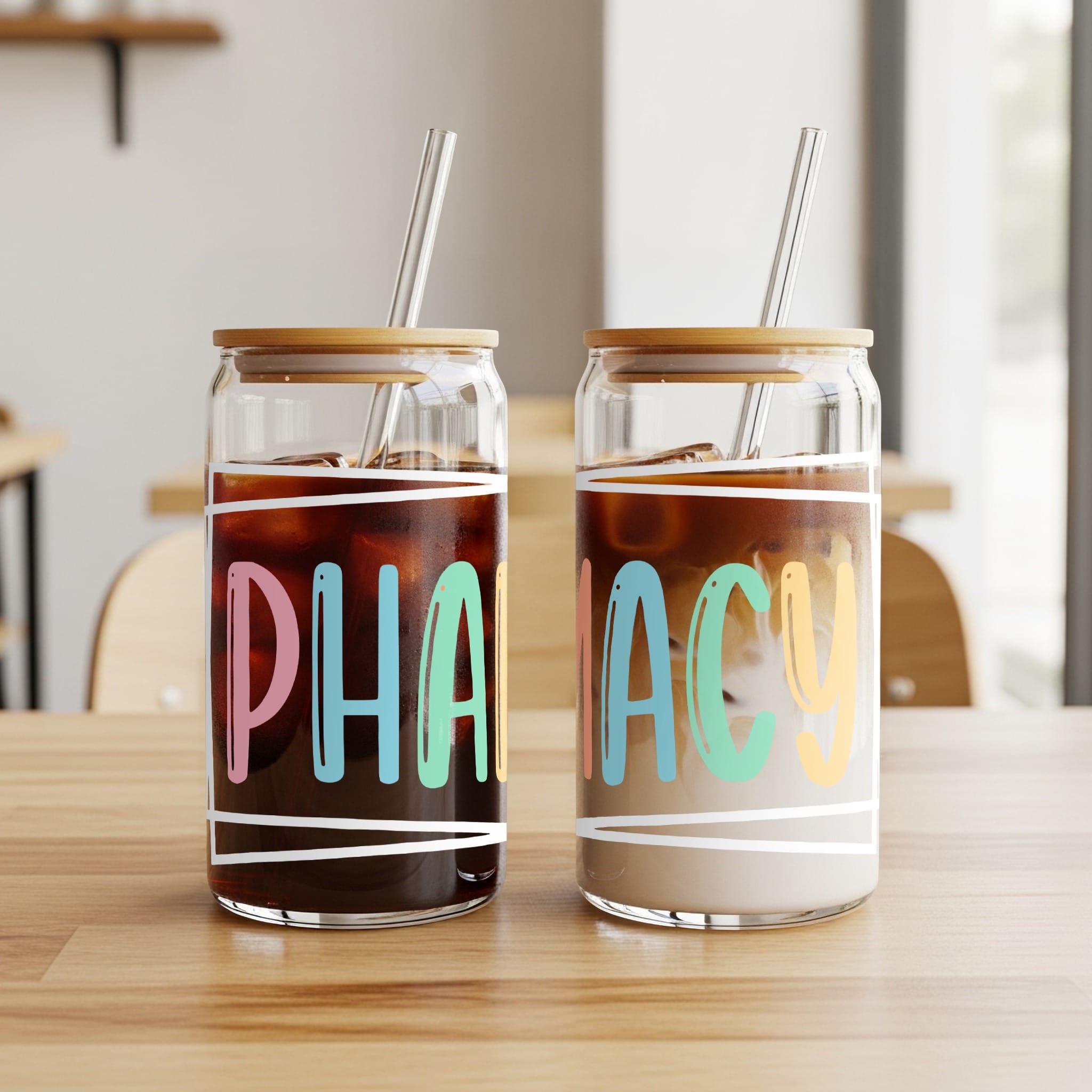 Two glass tumblers with bamboo lids, each with a straw and the word "PHARMACY" in colorful text.