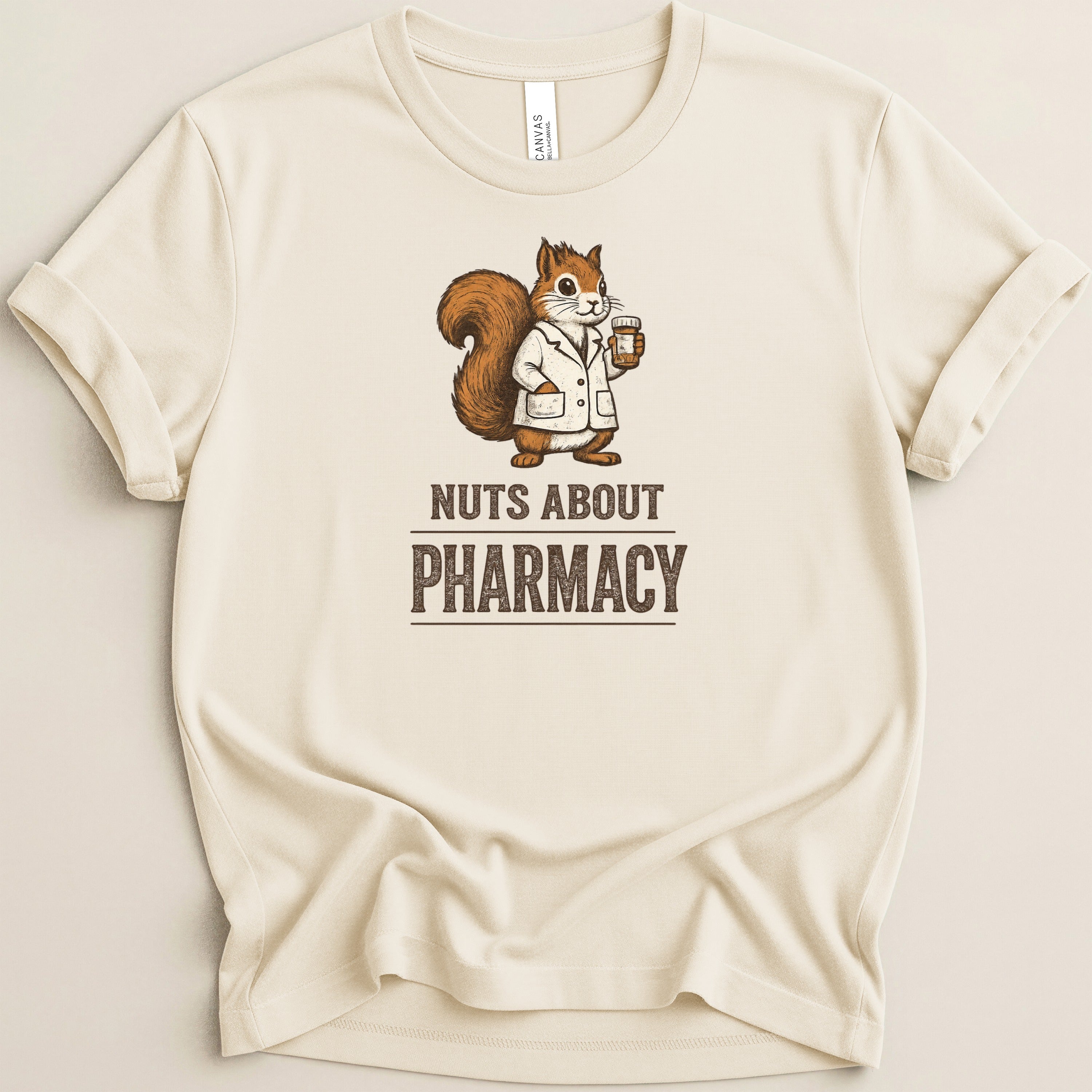 Cream t-shirt with a cartoon squirrel in a lab coat holding medication. Text reads "Nuts About Pharmacy".