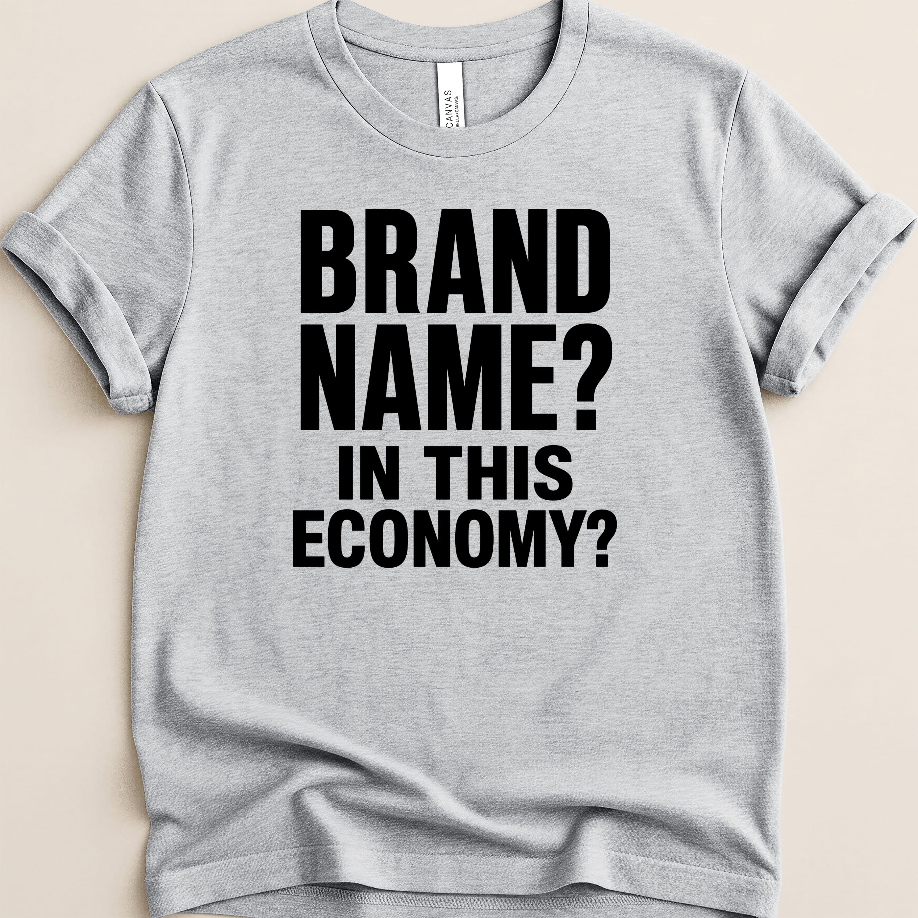 Grey t-shirt with bold black text "BRAND NAME? IN THIS ECONOMY?".