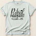 Retired Pharmacist text with pill on a light blue t-shirt.