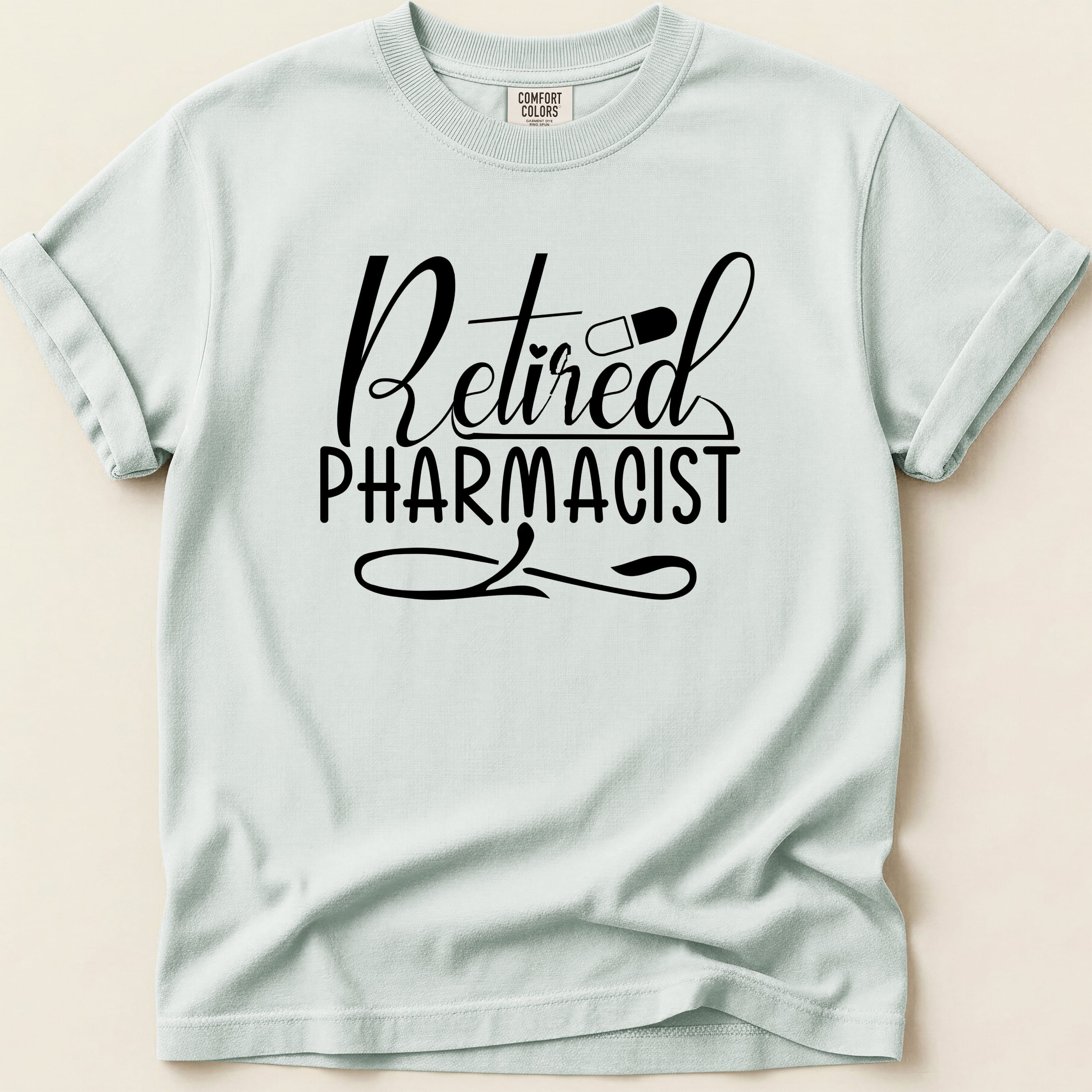 Retired Pharmacist text with pill on a light blue t-shirt.